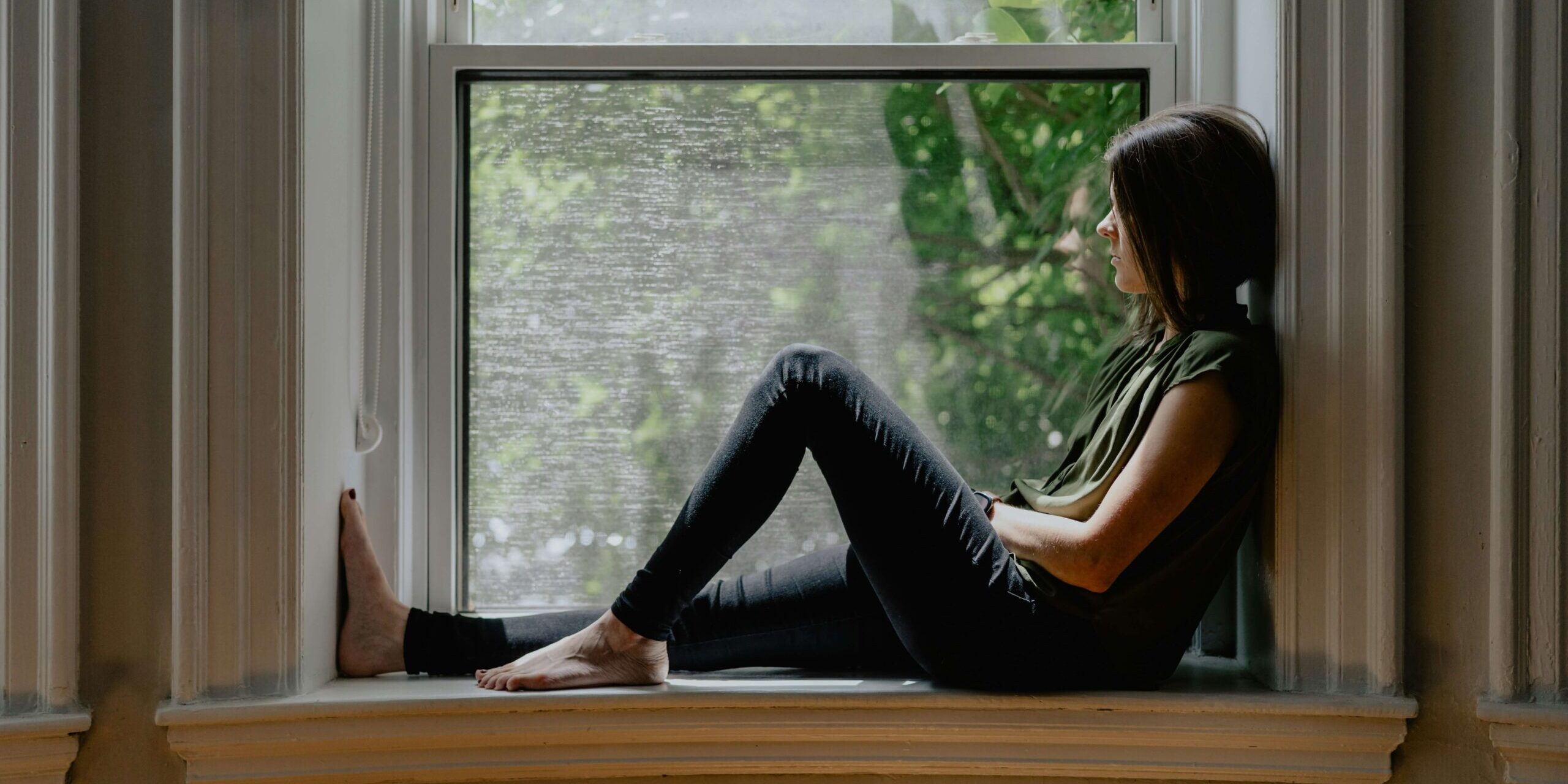 Woman looking thoughtfully out a window — difference between anxiety and an anxiety disorder